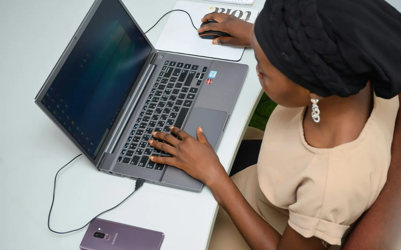 Mains sur le clavier d’un ordinateur portable, téléphone posé à côté