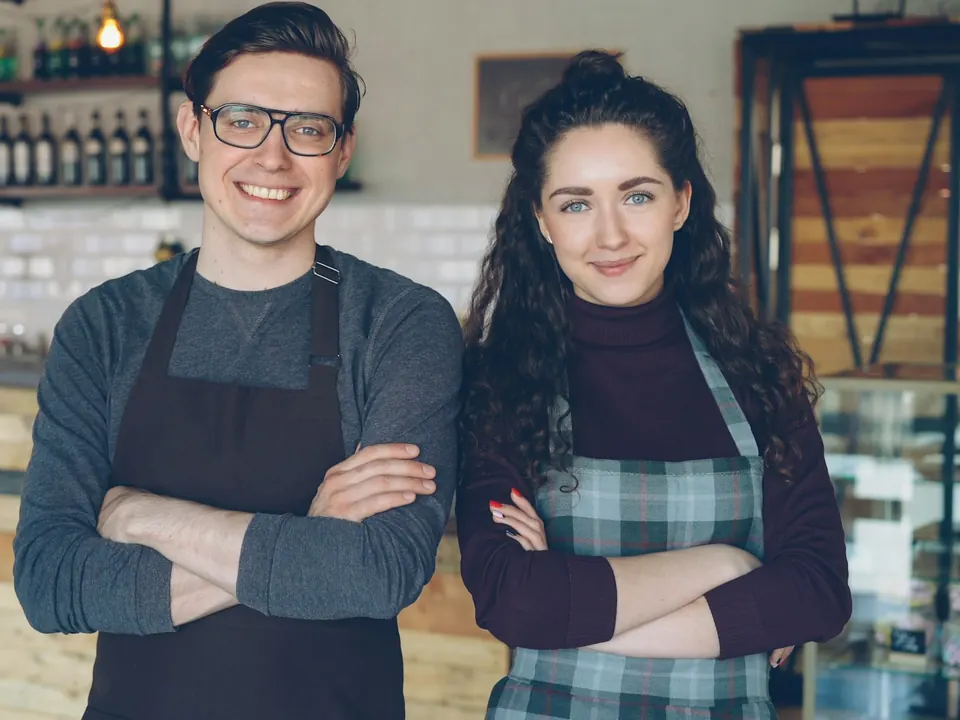 Deux gérants de café souriants derrière leur comptoir