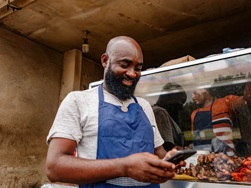 Restaurateur consultant son téléphone devant sa grillade