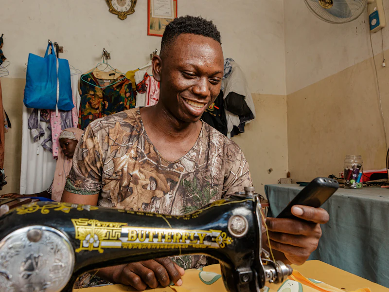 Couturier à sa machine, téléphone à la main